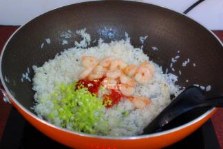 把炒过的虾仁、红辣椒末、葱白加入翻炒；