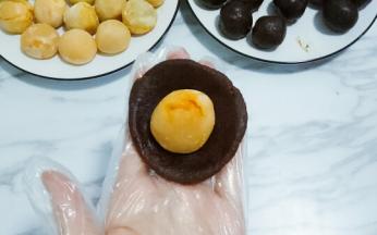 准备好蛋黄和豆沙，去豆沙一份，按扁放入咸鸭蛋黄