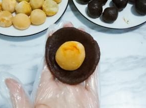 准备好蛋黄和豆沙，去豆沙一份，按扁放入咸鸭蛋黄
