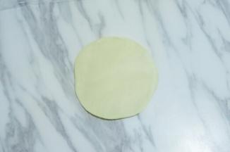 按扁，用擀面杖擀成中间稍厚，四周稍薄的面皮