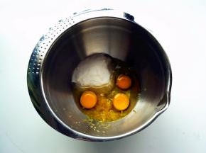 将鸡蛋、细砂糖、清水（用等量的纯牛奶代替更香），柠檬皮屑放入打蛋盆中。