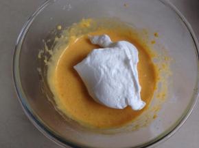 取三分之一打发好的蛋白霜入蛋黄糊里，用刮刀从底部向上翻拌均匀