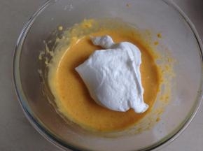 取三分之一打发好的蛋白霜入蛋黄糊里，用刮刀从底部向上翻拌均匀