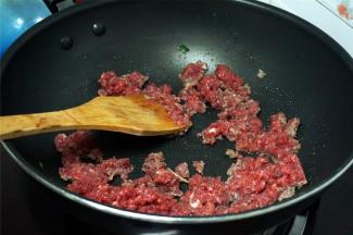 烧红锅，加入适量的花生油，然后加入瘦肉碎，快速翻炒。