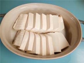 泡好的豆腐切成1厘米左右的厚度。并排放入碗中。