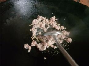 下入肉末翻炒变色后淋入料酒。