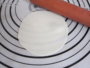 取一第张饺子皮，用擀面杖将边沿稍稍擀薄。