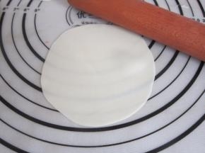取一第张饺子皮，用擀面杖将边沿稍稍擀薄。