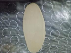 取一个面团收口朝上，从中间上下轻轻擀，擀成牛舌状。