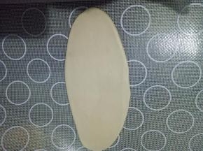 取一个面团收口朝上，从中间上下轻轻擀，擀成牛舌状。