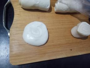 切面朝上先按扁，用擀面杖擀成中间厚，四周薄的面片。