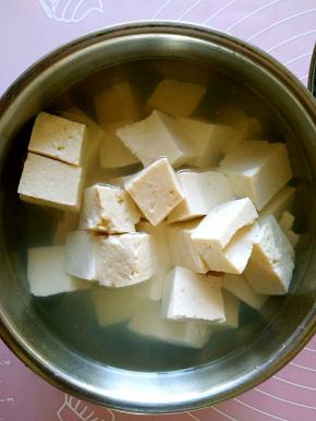 老豆腐切成小块，放在开水中加入少许盐，泡10分钟。