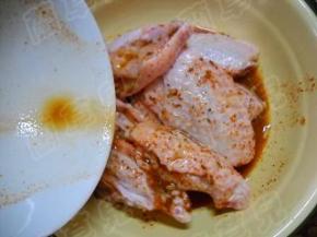 鸡翅中放入碗中，倒入调好的味汁。 充分揉匀，方便其入味。