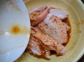 鸡翅中放入碗中，倒入调好的味汁。 充分揉匀，方便其入味。