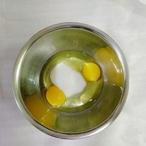 鸡蛋打入盆中，加入50g白砂糖（在准备一个盆里面放入热水，把鸡蛋盆放入热水盆中，有利于全蛋打发）