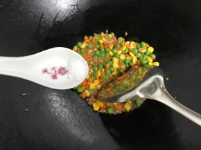 再把玉米粒、青豆和胡萝卜放进去翻炒均匀后加少许盐调味。