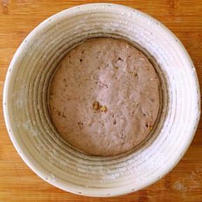 把整形好的面包胚光滑的一面向下放在发酵蓝中并用手轻轻按压。