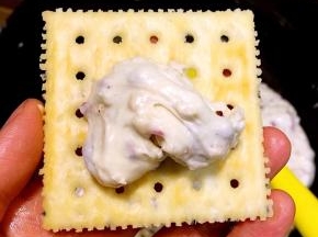 取适量炒好的牛扎糖放在饼干上，大概10克左右，具体的随个人喜好