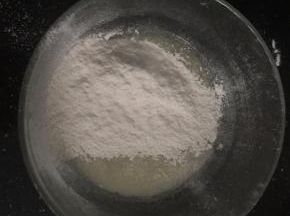 在油水混合物中筛入低筋面粉，用手动打蛋器无规则的搅拌成均匀细腻的面糊。