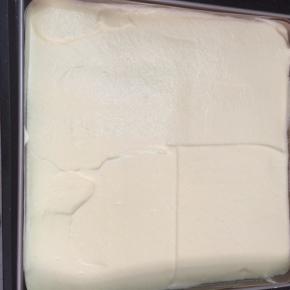 把面糊从高处倒入金盘中，刮平表面，轻震出大气泡。