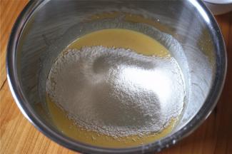 往搅拌好的蛋黄液中筛入低粉和粟粉（玉米淀粉）。