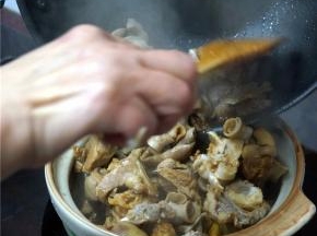 将炒锅里的羊肉转移到砂锅上焖煮。