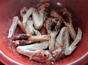 用一个大容器腌制鸭头。先铺一层鸭头。