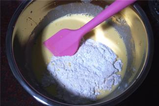 往搅拌好的蛋黄液中筛入低粉和粟粉（玉米淀粉），切拌成无颗粒的糊状。