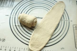 取一个面团，按扁擀成长方形厚面皮，卷起来。