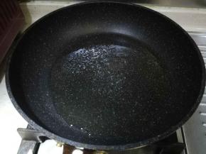 平底锅中加入适量玉米油，开火，油温五分热时加入少许盐，晃动平底锅使盐巴在锅里均匀散开，可以防粘