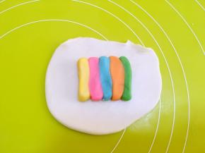 取一份水油皮材料，擀成长方形，之后放上一条彩色油酥条