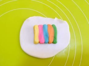 取一份水油皮材料，擀成长方形，之后放上一条彩色油酥条