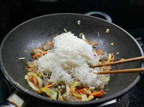 接着将细粉丝放入，用筷子和铲子帮忙快速翻炒均匀即可出锅