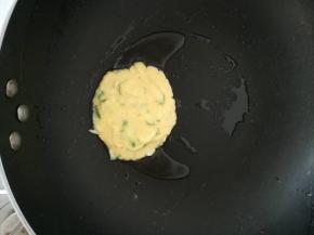 用勺子取一勺面糊倒入锅中。