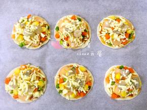 上面再撒一层芝士碎，然后把鲜虾丁摆在上面，再在每个鲜虾丁上撒少量芝士碎。