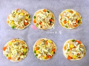 上面再撒一层芝士碎，然后把鲜虾丁摆在上面，再在每个鲜虾丁上撒少量芝士碎。