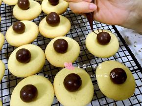 用巧克力酱在麦丽素的两侧分别挤上蜘蛛腿。