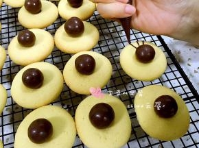 用巧克力酱在麦丽素的两侧分别挤上蜘蛛腿。