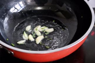 锅中放油烧热，葱花和蒜瓣爆香
