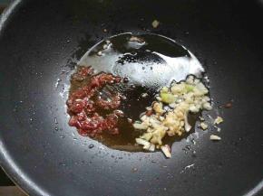 锅中倒少许油，下郫县豆瓣酱炒出红油，下剩余的葱蒜末爆香。