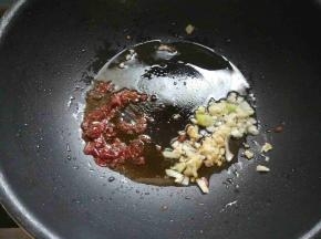锅中倒少许油，下郫县豆瓣酱炒出红油，下剩余的葱蒜末爆香。
