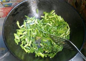 锅中倒少许油，加入蒜苔翻炒。