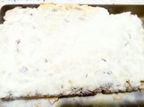 将一些奶粉过筛后撒在压平的酥上，再用压板压紧