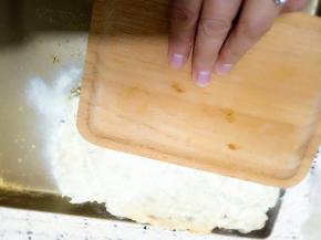 我用的木托盘，压平压实把奶粉压在酥上面。以后翻面在撒上奶粉，继续压实。