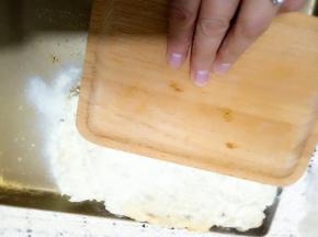 我用的木托盘，压平压实把奶粉压在酥上面。以后翻面在撒上奶粉，继续压实。