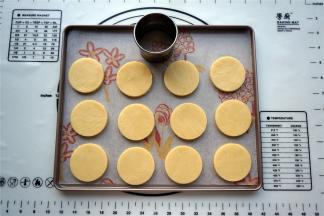 取出冷冻至硬的面片，用圆形饼干模具印出饼胚，放入烤盘中。