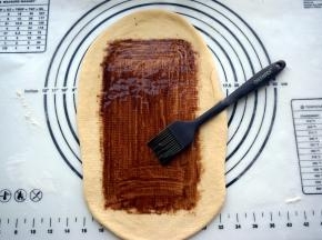 宽度确定后，往前后擀开，将面片擀薄，然后抹上一层巧克力酱。