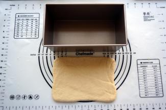 松弛完毕后，取一个面团，擀成宽度与吐司盒差不多的长方形。