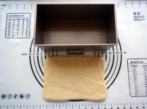 松弛完毕后，取一个面团，擀成宽度与吐司盒差不多的长方形。