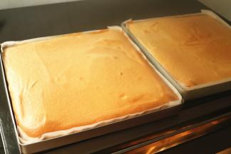 烤架上铺一层油纸，出炉的蛋糕片马上倒扣，这样表皮会被黏掉，卷起来就很白净了。